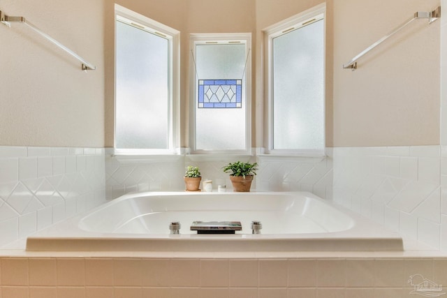 bathroom with tiled tub and plenty of natural light