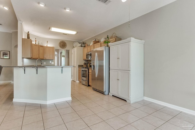 kitchen with light tile patterned floors, crown molding, appliances with stainless steel finishes, and a breakfast bar