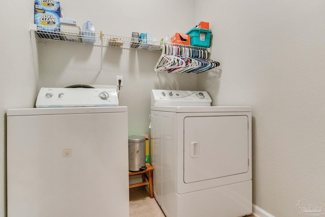 laundry area with independent washer and dryer and light tile patterned floors