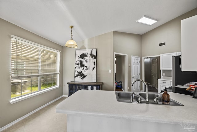 8187 Lode Star Ave, Pensacola, FL 32514 - kitchen with freestanding refrigerator, lofted ceiling, white cabinets, a sink, and baseboards