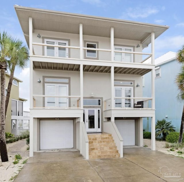 raised beach house featuring a balcony and a garage