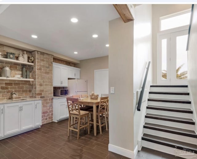 kitchen with decorative backsplash, sink, beam ceiling, white fridge, and white cabinetry