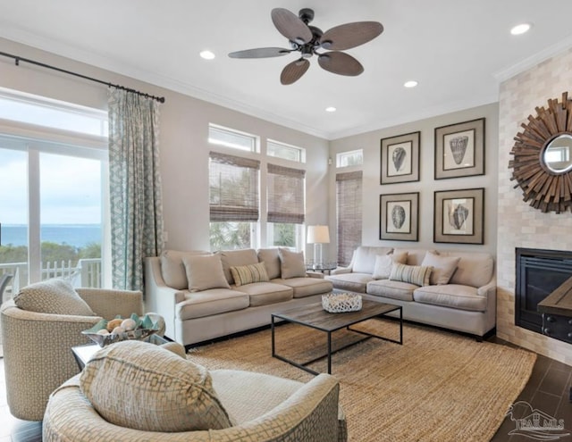 living room with ceiling fan, a fireplace, and ornamental molding