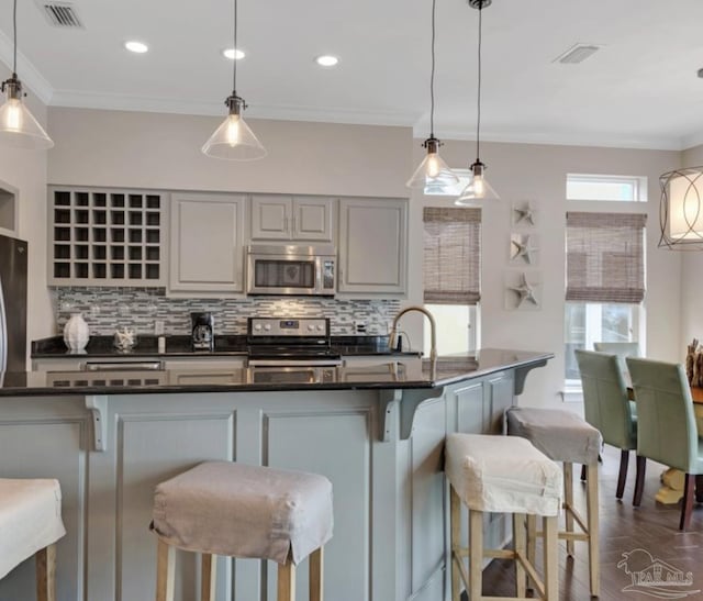 kitchen with a kitchen bar, tasteful backsplash, stainless steel appliances, and decorative light fixtures