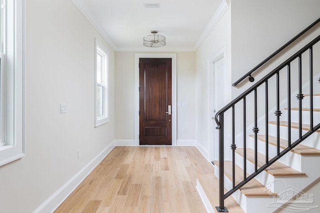 foyer entrance with ornamental molding and light hardwood / wood-style floors