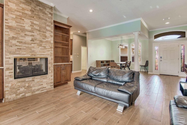 living room featuring a multi sided fireplace, light wood-type flooring, ornamental molding, and decorative columns