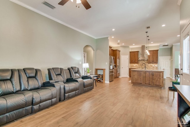 living room with sink, light wood-type flooring, ceiling fan, and ornamental molding