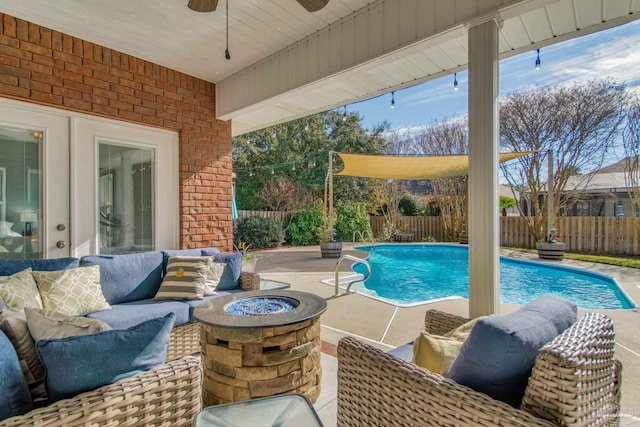 view of swimming pool with ceiling fan, an outdoor living space with a fire pit, and a patio area