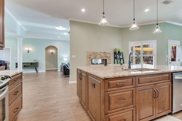 kitchen with sink, decorative light fixtures, a kitchen island with sink, and light stone counters