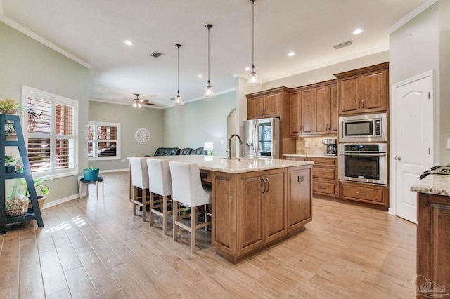 kitchen featuring appliances with stainless steel finishes, pendant lighting, light stone countertops, and ceiling fan