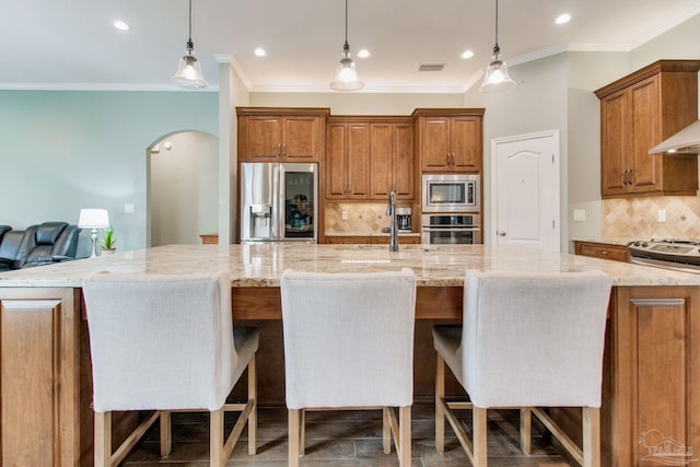 kitchen featuring a large island, appliances with stainless steel finishes, a breakfast bar, and tasteful backsplash