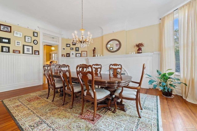 dining space with hardwood / wood-style flooring and a notable chandelier