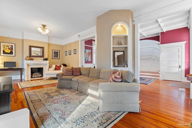 living room with a fireplace, beamed ceiling, and hardwood / wood-style floors