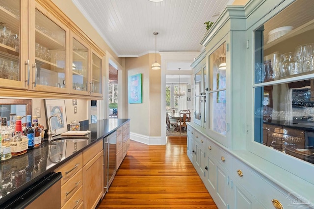 bar with stainless steel dishwasher, hardwood / wood-style flooring, pendant lighting, ornamental molding, and sink