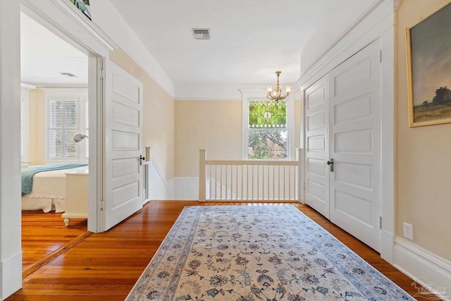 entryway with ornamental molding, a notable chandelier, and hardwood / wood-style floors