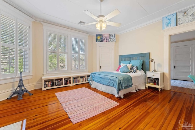 bedroom with multiple windows, hardwood / wood-style flooring, crown molding, and ceiling fan