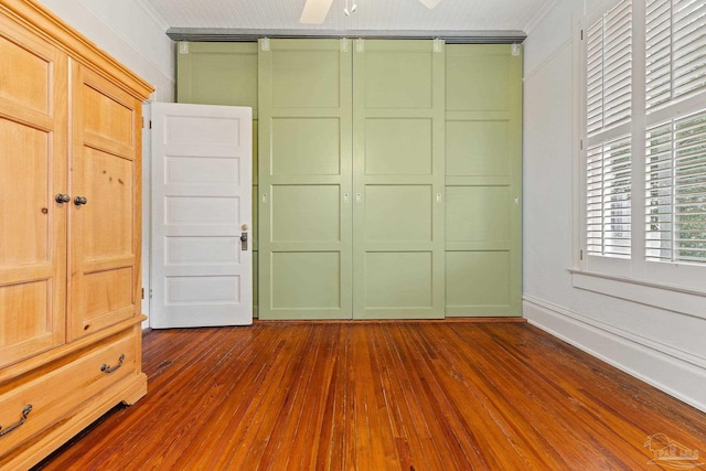 unfurnished bedroom featuring dark hardwood / wood-style flooring, a closet, crown molding, and ceiling fan