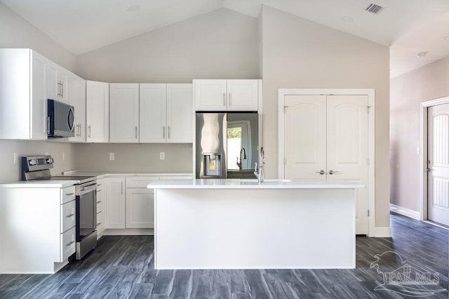 kitchen with appliances with stainless steel finishes, dark hardwood / wood-style flooring, white cabinetry, and a kitchen island with sink