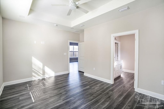 unfurnished room with a raised ceiling, ceiling fan, and dark wood-type flooring