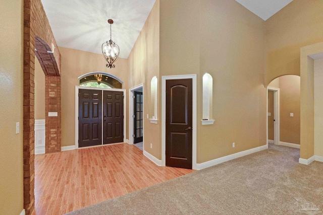 carpeted entryway featuring high vaulted ceiling and a notable chandelier