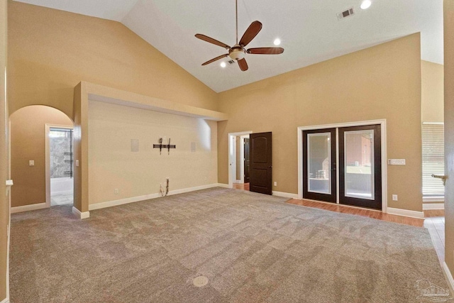 carpeted empty room with high vaulted ceiling, ceiling fan, and french doors