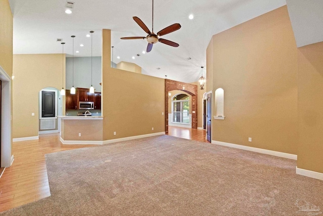 unfurnished living room featuring ceiling fan, light hardwood / wood-style flooring, and high vaulted ceiling