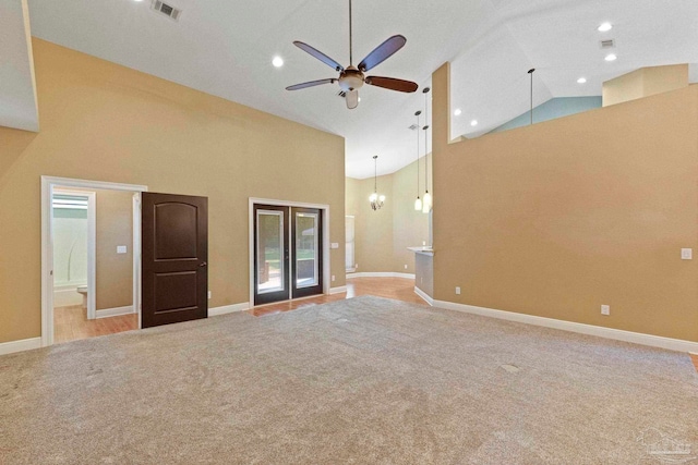 unfurnished living room featuring ceiling fan, light colored carpet, french doors, and high vaulted ceiling