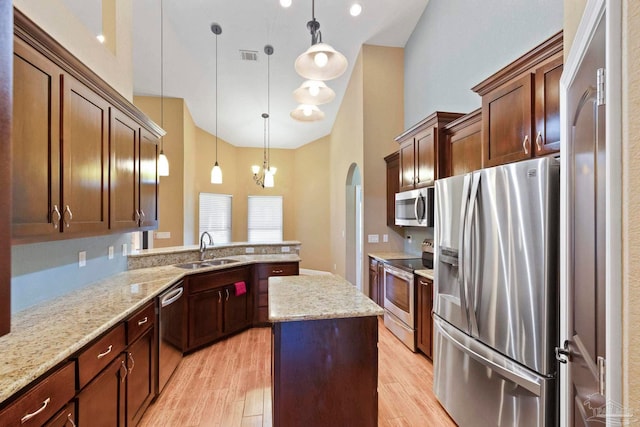 kitchen with appliances with stainless steel finishes, sink, light hardwood / wood-style flooring, and decorative light fixtures