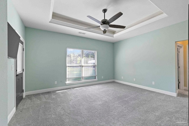 carpeted empty room with ceiling fan and a raised ceiling