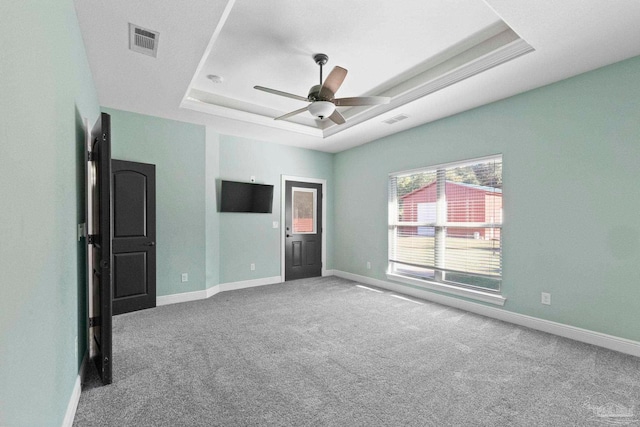 unfurnished bedroom with a raised ceiling, carpet, and ceiling fan