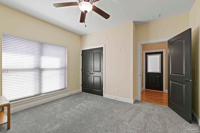 unfurnished bedroom with ceiling fan, light colored carpet, and a closet