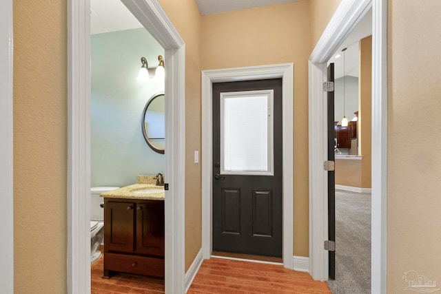 doorway to outside with light wood-type flooring and sink