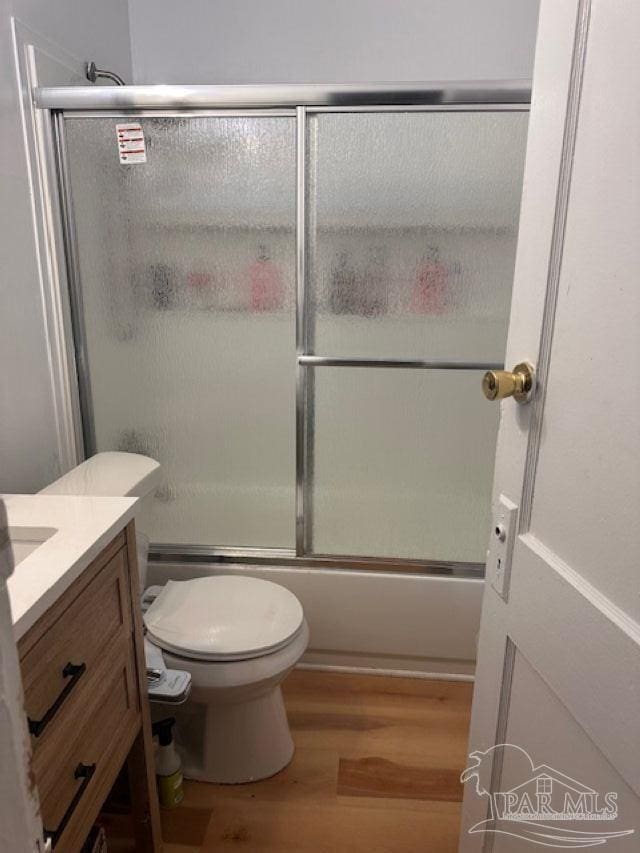 full bathroom featuring toilet, vanity, combined bath / shower with glass door, and hardwood / wood-style flooring