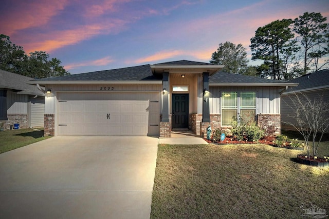 prairie-style house with a front lawn, stone siding, board and batten siding, an attached garage, and driveway