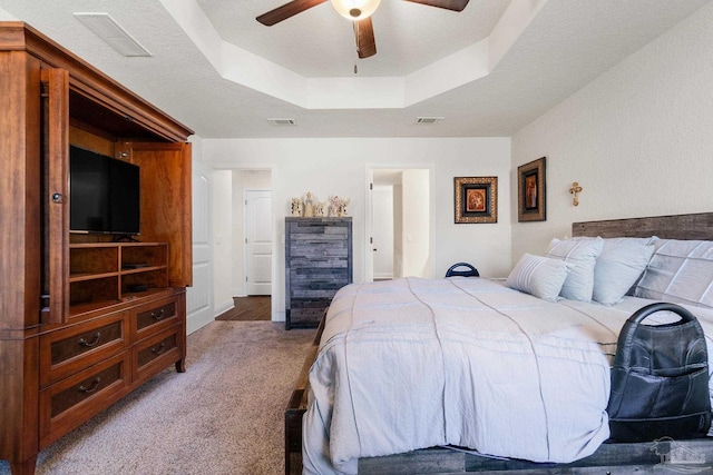 bedroom with visible vents, a tray ceiling, and light colored carpet