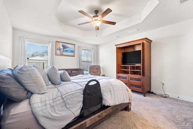 bedroom featuring a ceiling fan, visible vents, light colored carpet, a raised ceiling, and baseboards