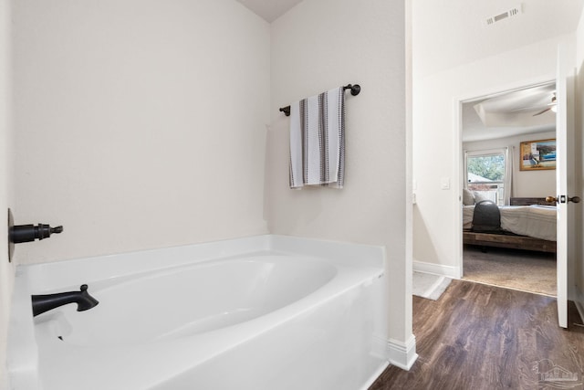 ensuite bathroom with a garden tub, visible vents, wood finished floors, baseboards, and ensuite bath