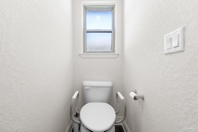 bathroom featuring a textured wall and toilet