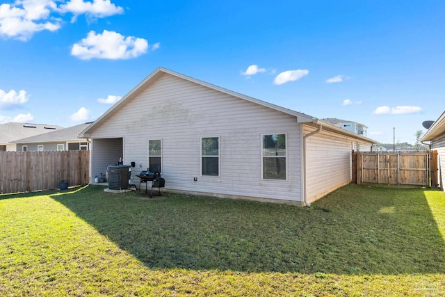 rear view of house featuring a lawn, cooling unit, and a fenced backyard