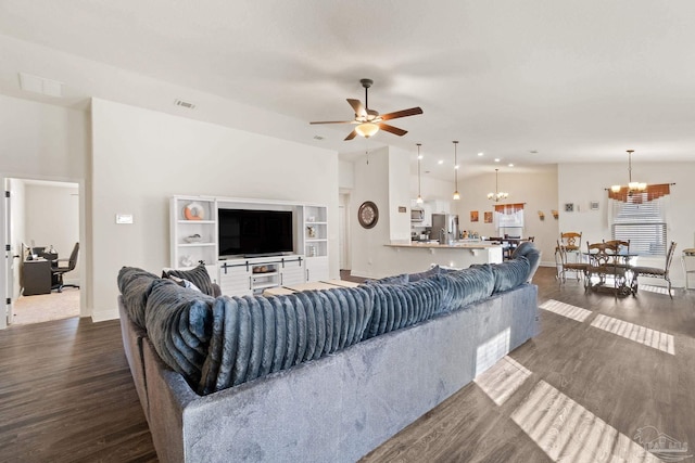 living room featuring baseboards, dark wood finished floors, ceiling fan with notable chandelier, and visible vents