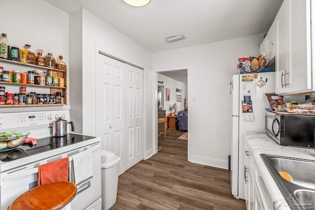 kitchen with sink, white cabinets, dark hardwood / wood-style floors, and white appliances