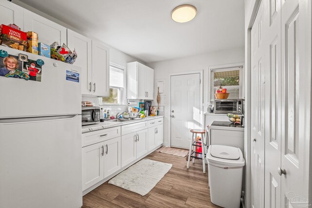 kitchen with white fridge, a healthy amount of sunlight, white cabinetry, and light wood-type flooring