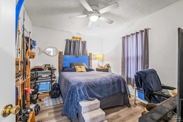 bedroom with ceiling fan, hardwood / wood-style flooring, and a textured ceiling