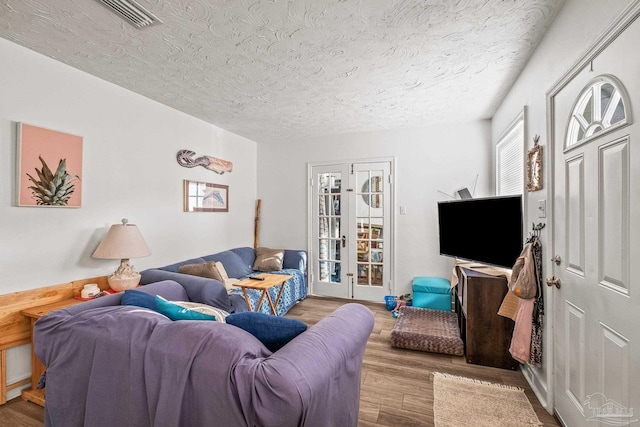 living room featuring french doors, wood-type flooring, and a textured ceiling