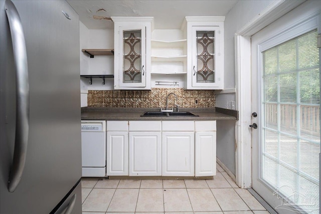 kitchen with dishwasher, sink, light tile patterned floors, white cabinetry, and stainless steel refrigerator