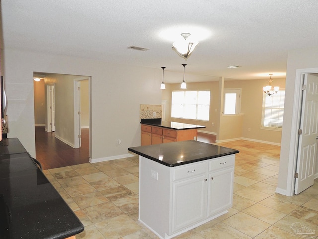 4814 Belvedere Cir, Pace, FL 32571 - kitchen with dark countertops, a center island, hanging light fixtures, white cabinetry, and a chandelier