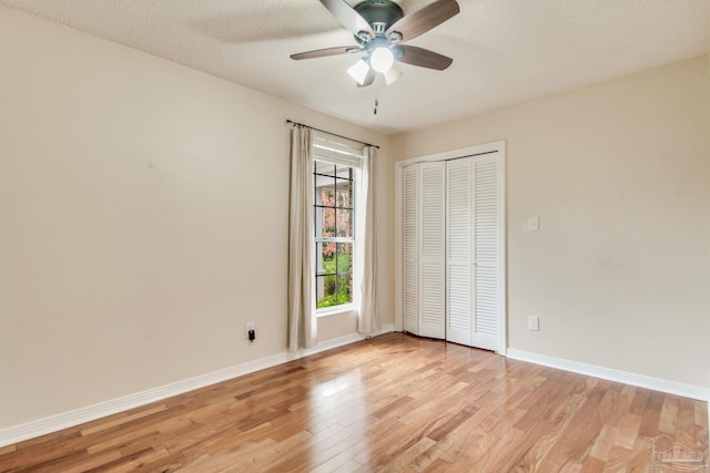 unfurnished bedroom featuring ceiling fan, a closet, a textured ceiling, and light hardwood / wood-style flooring