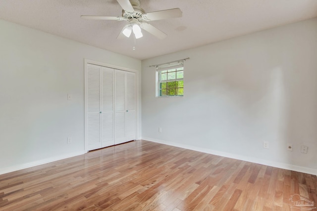 unfurnished bedroom with ceiling fan, a closet, a textured ceiling, and light hardwood / wood-style flooring