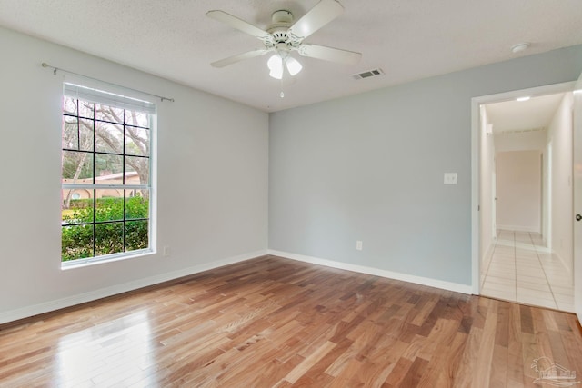 unfurnished room featuring a textured ceiling, light hardwood / wood-style flooring, ceiling fan, and a healthy amount of sunlight