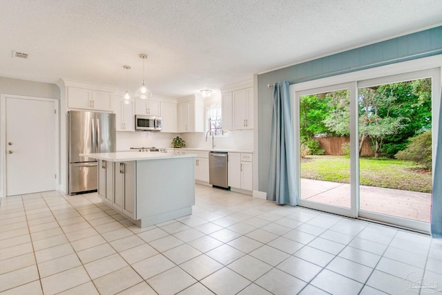 kitchen with white cabinetry, a center island, stainless steel appliances, decorative light fixtures, and light tile patterned floors